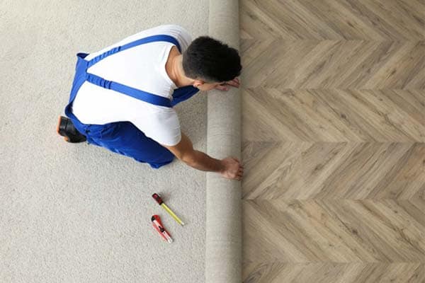 A carpet fitter unrolling a new carpet.