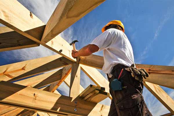 A tradesperson working on a wooden structure of a house
