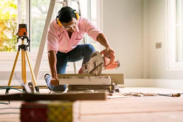 A self-employed handyman using a circular saw. 