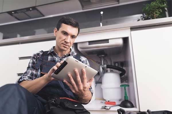 A plumber enters details of a job he has just completed into his tablet