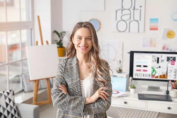 Smiling young female self-employed interior designer in her office.