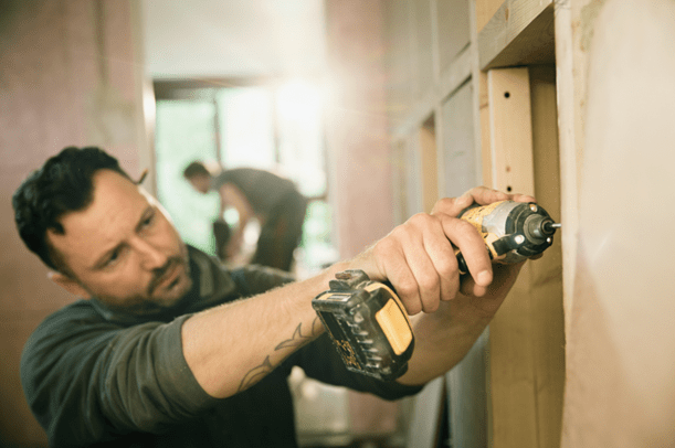 A tradesman drilling into a wall.
