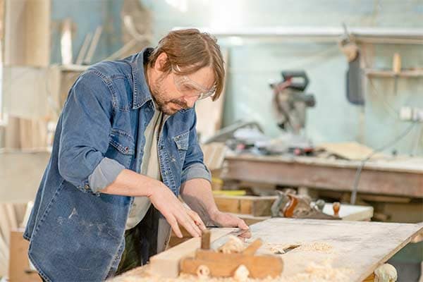 A male joiner in his workshop measuring wood.