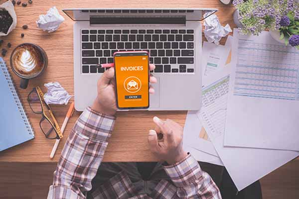 A tradesman holding his phone and using an invoicing app.