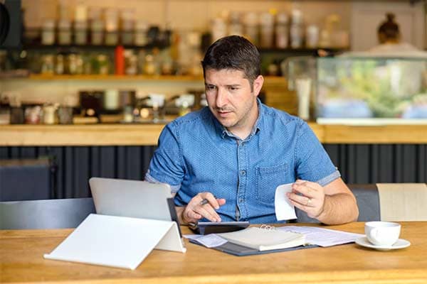 A self-employed man sat at his desk, sorting out his tax bill.