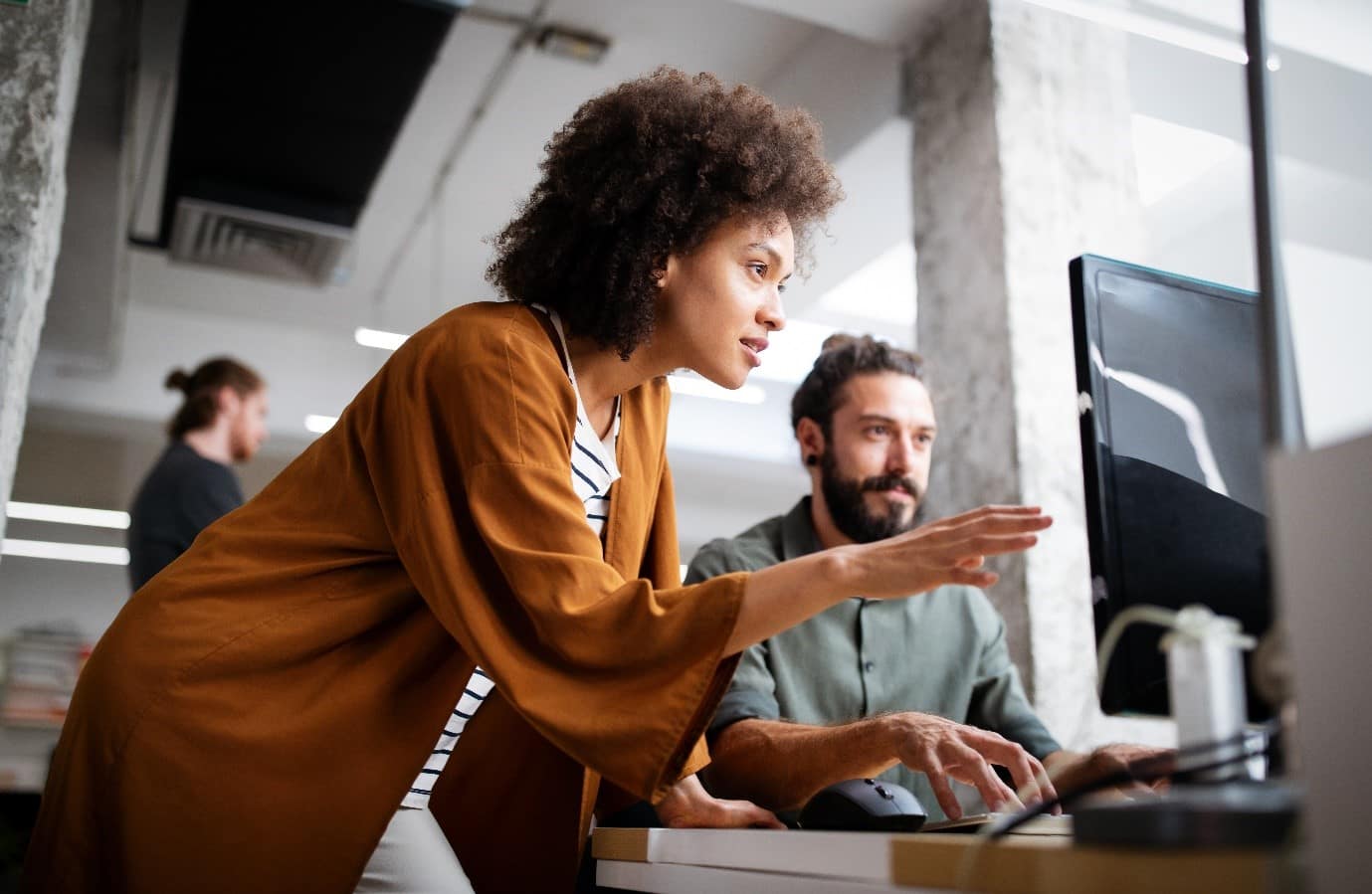 Two people in an office in front of a computer screen