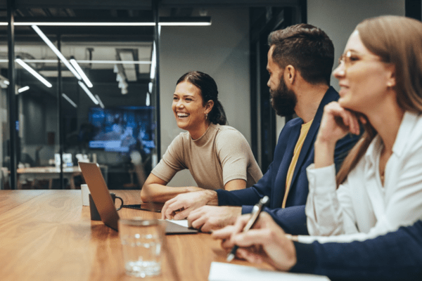 Three people sat in a meeting room, all smiling