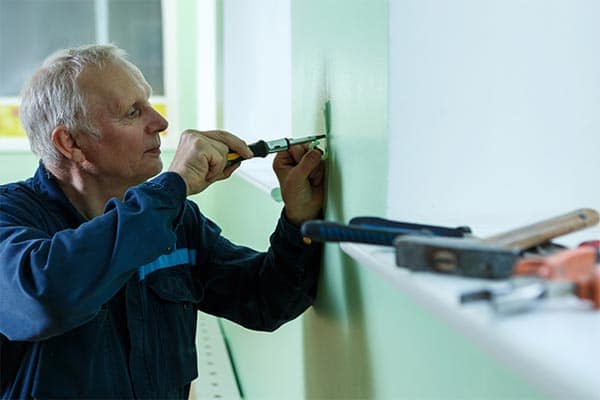 A self-employed handyman on a job filling a wall.