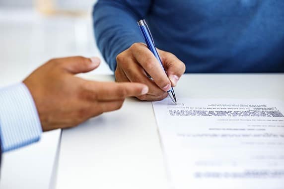 Two people sat at a table signing a business contract