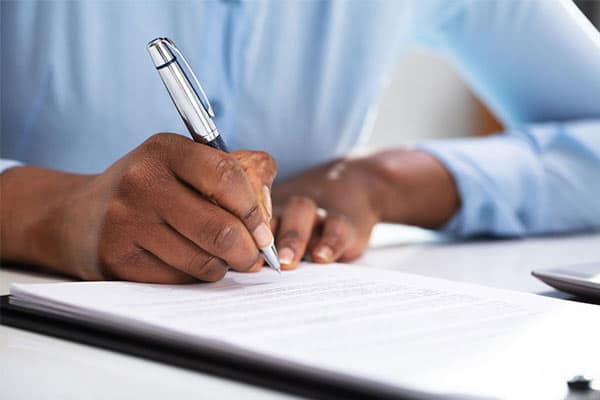 Close up of end client's hand writing a Status Determination Statement.