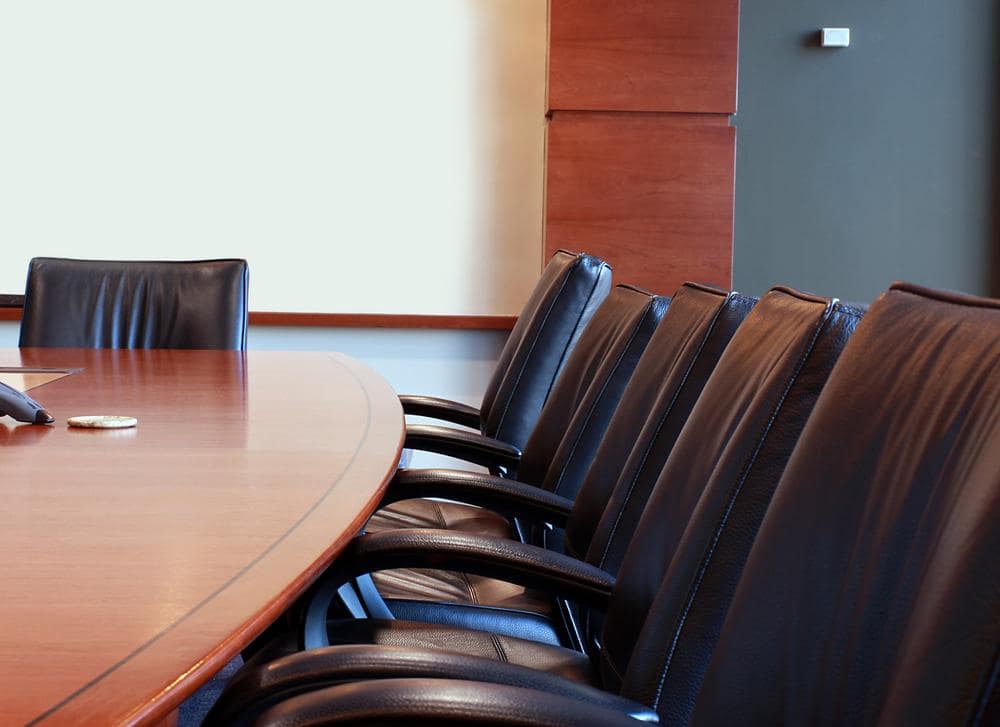 A boardroom with a large table and multiple chairs