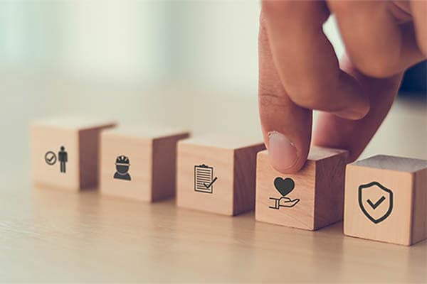 A hand picking up a wooden block with a health symbol printed on the front.