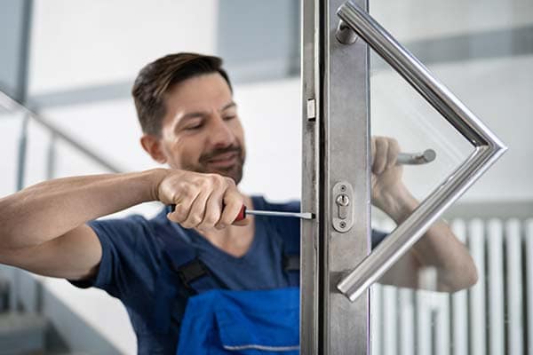 A locksmith fixing the locks on a door in a client's home.