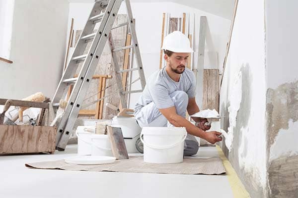 A painter in a customer's home painting a wall.