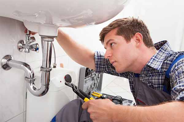 A plumber in a customer's home fixing a sink.