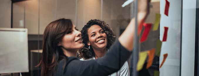 Two woman brainstorming ideas with post-it notes