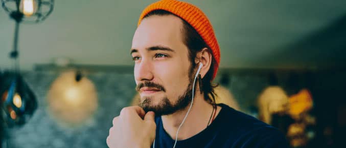 Man with earphones, looking thoughtful while working indoors.