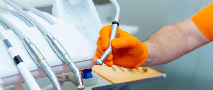 Self-employed dentist holding a dental drill tool in a clinic.