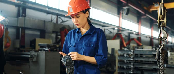 Self-employed female engineer working in a manufacturing facility wearing a hard hat.