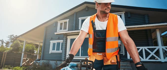 Self-employed construction worker using power tools outside a house renovation project.