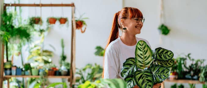 Self-employed plant shop owner smiling while working in her indoor plant store.