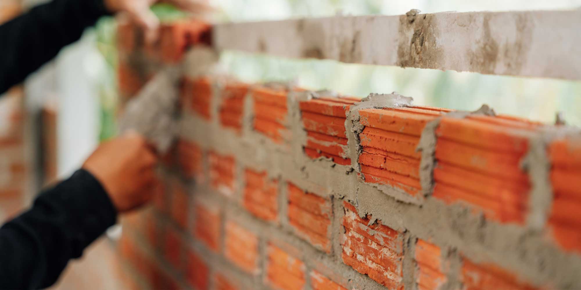Bricklayer applying mortar to a brick wall