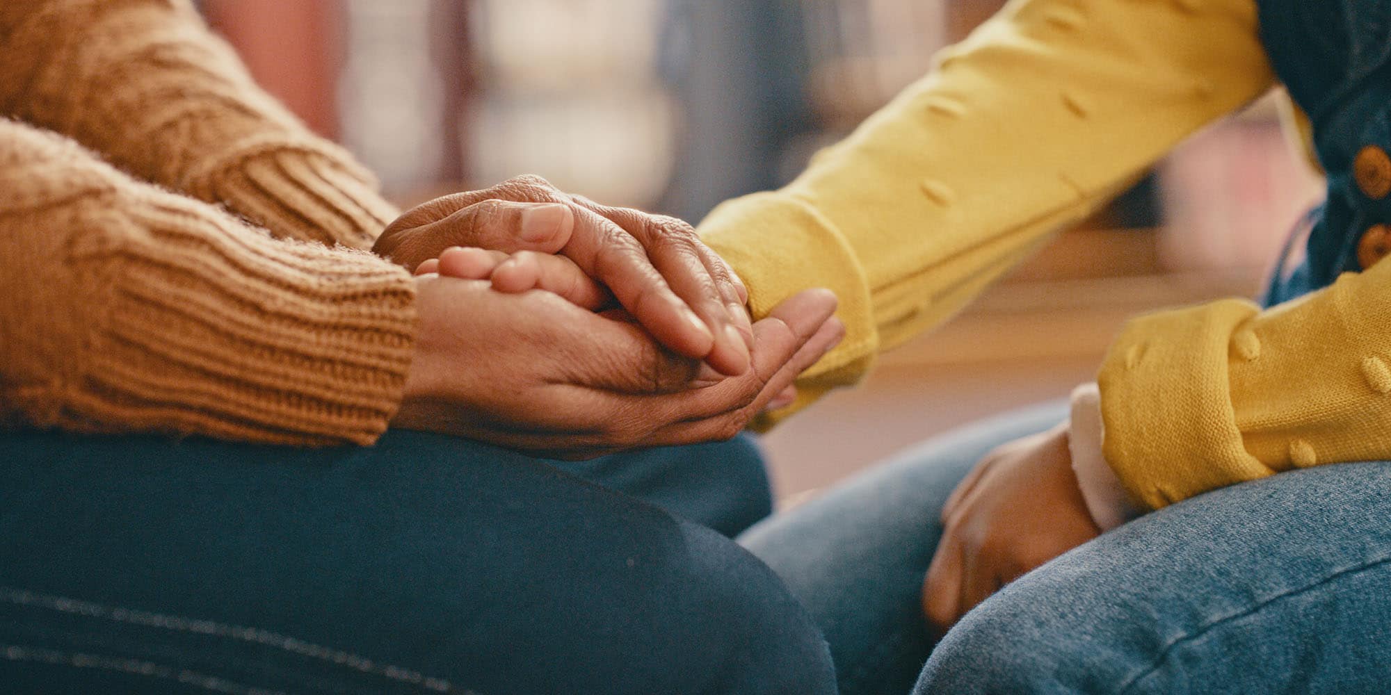 Close-up of two people sitting and holding hands