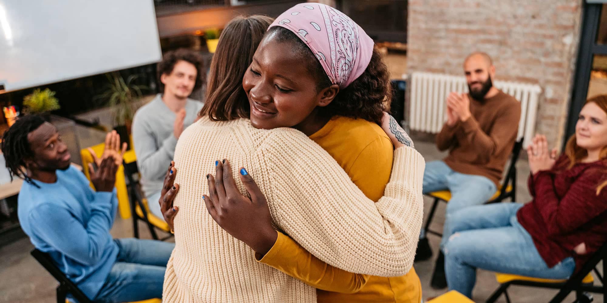 Two people standing and hugging in a support group