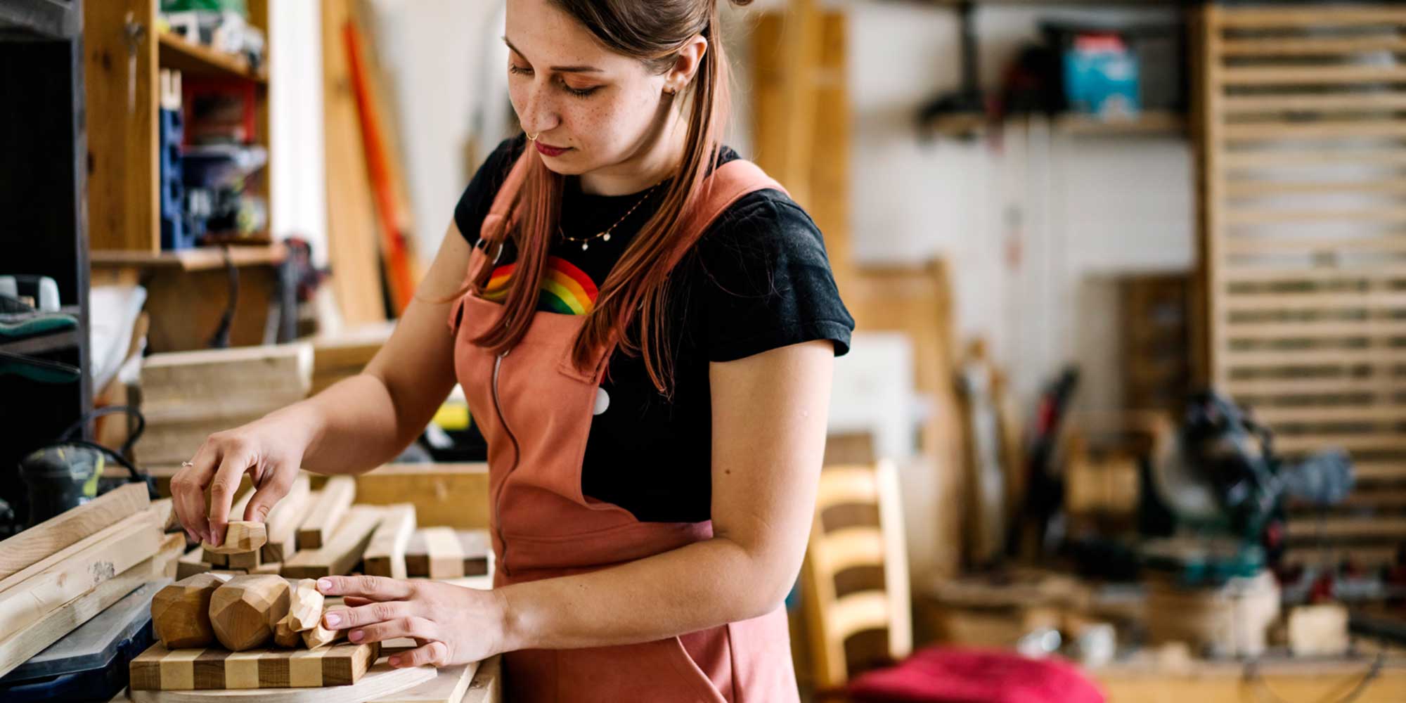 Woman organizing handmade wooden pieces on a workbench