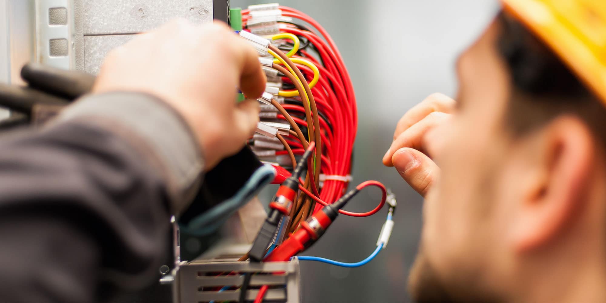 Electrical engineer working with wiring connections inside an electrical control panel