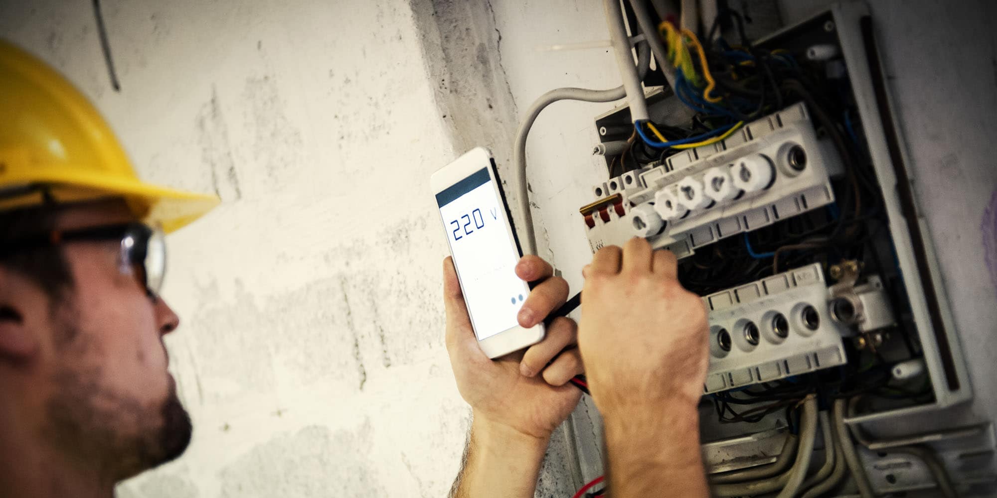 Electrician measuring voltage and adjusting connections inside an electrical distribution panel