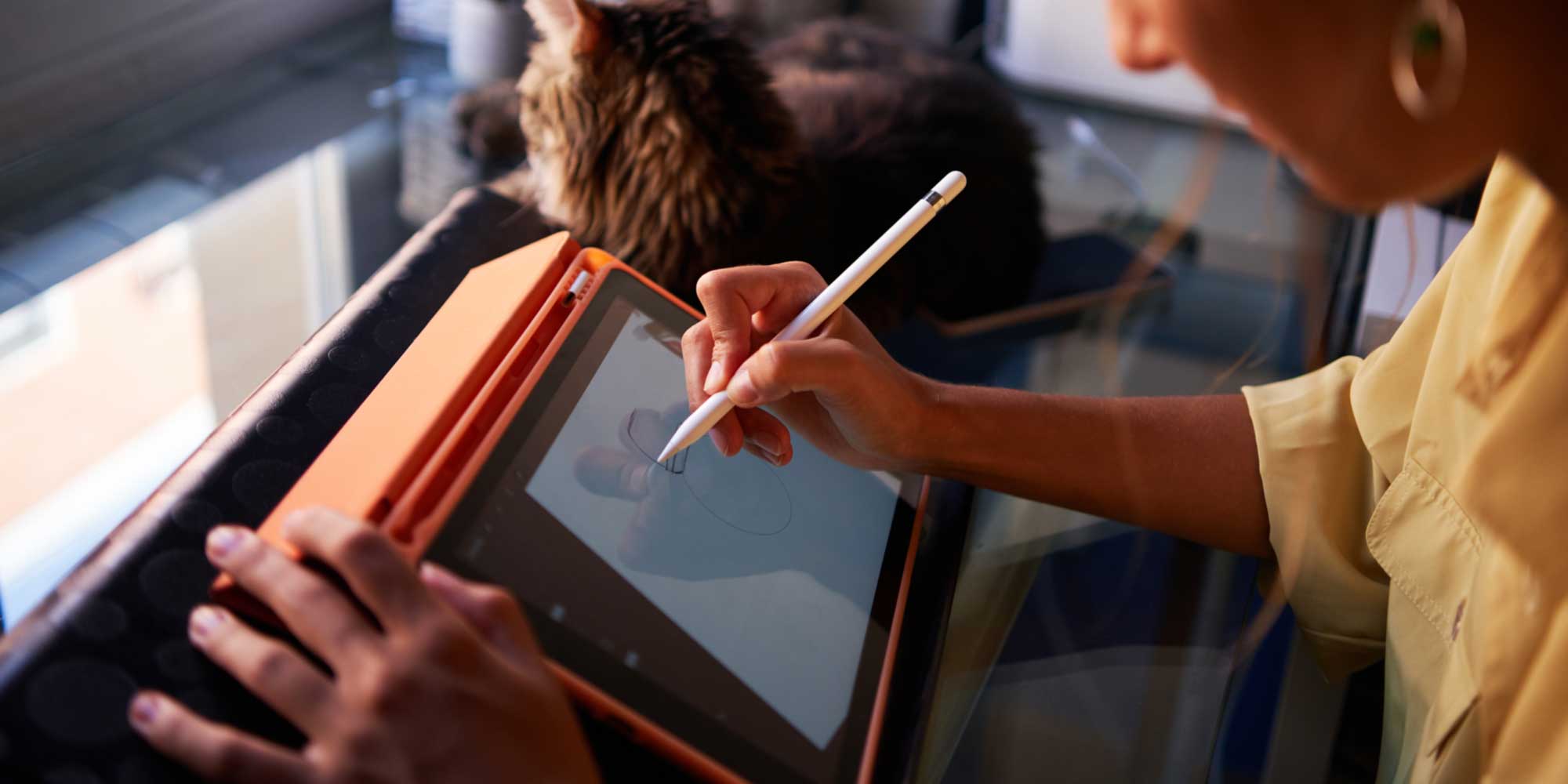 Person using a stylus to draw on a tablet screen placed on a desk