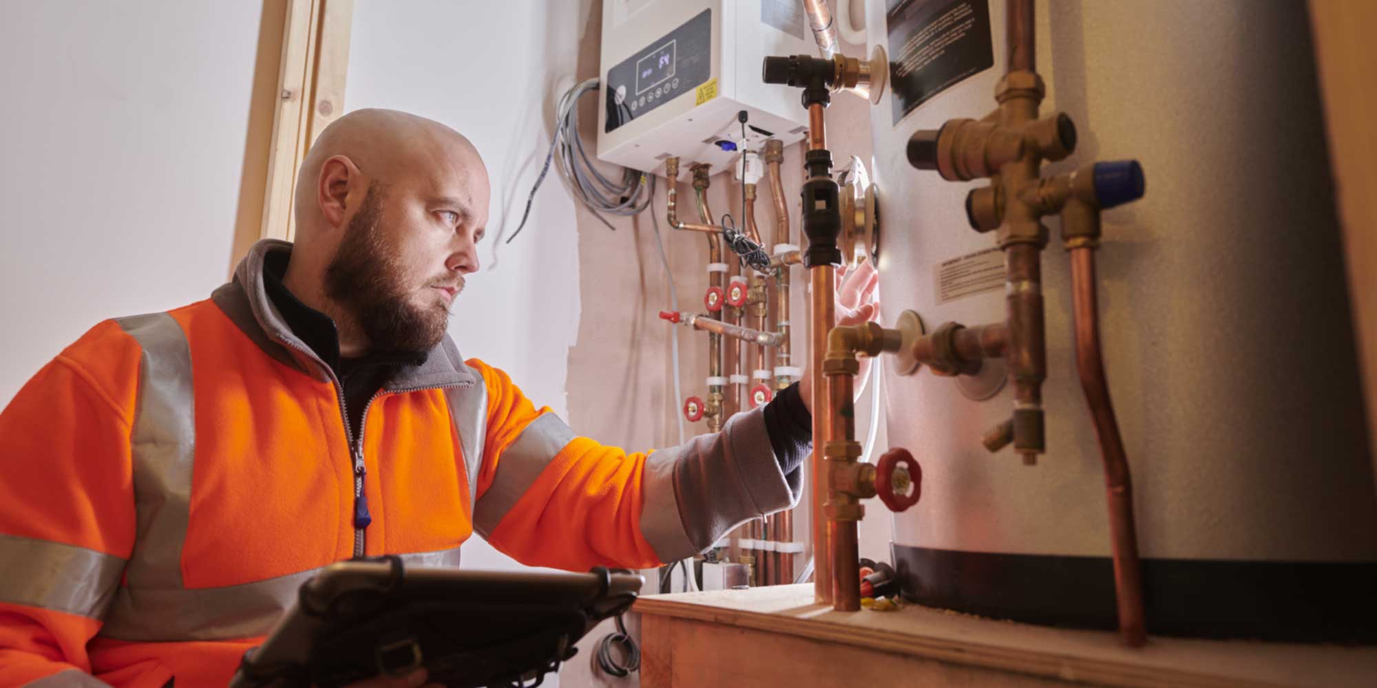 HVAC engineer inspecting and servicing a heating system and pipework inside a building