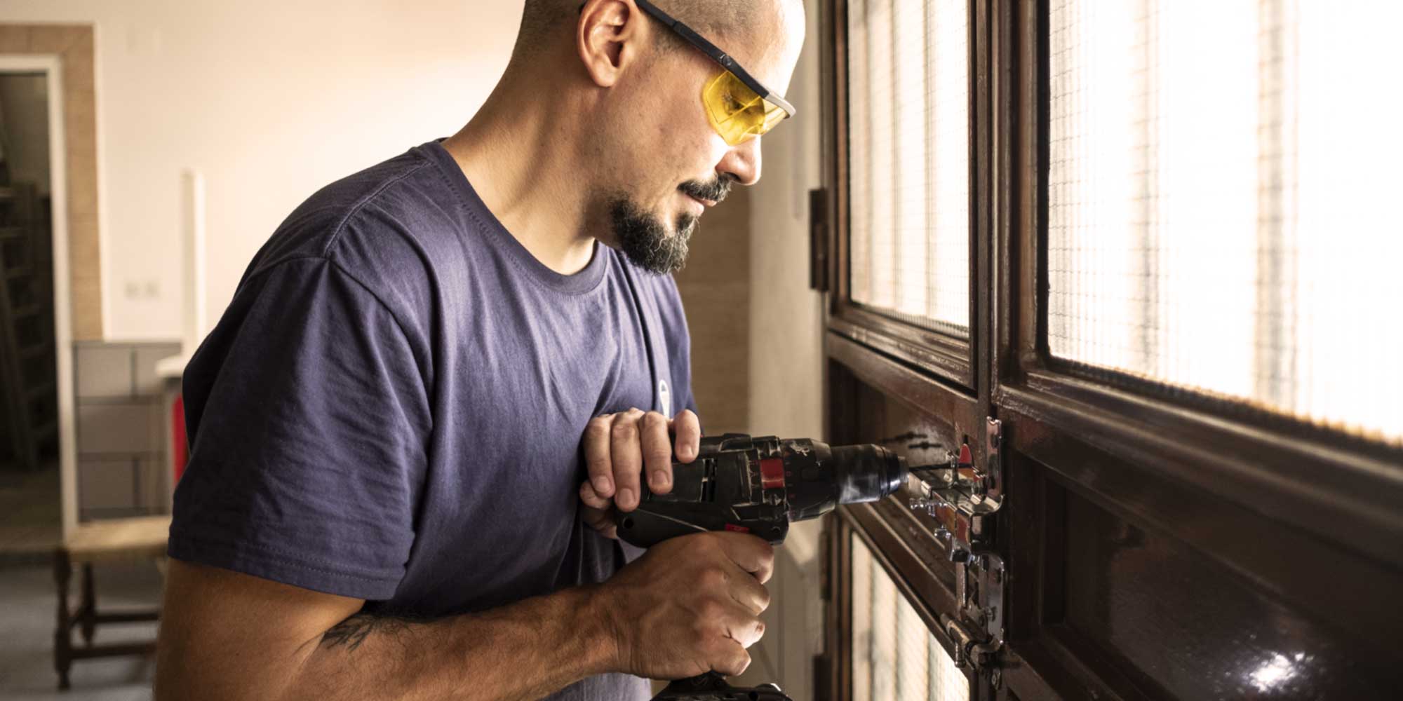Locksmith drilling while installing a new lock on a door