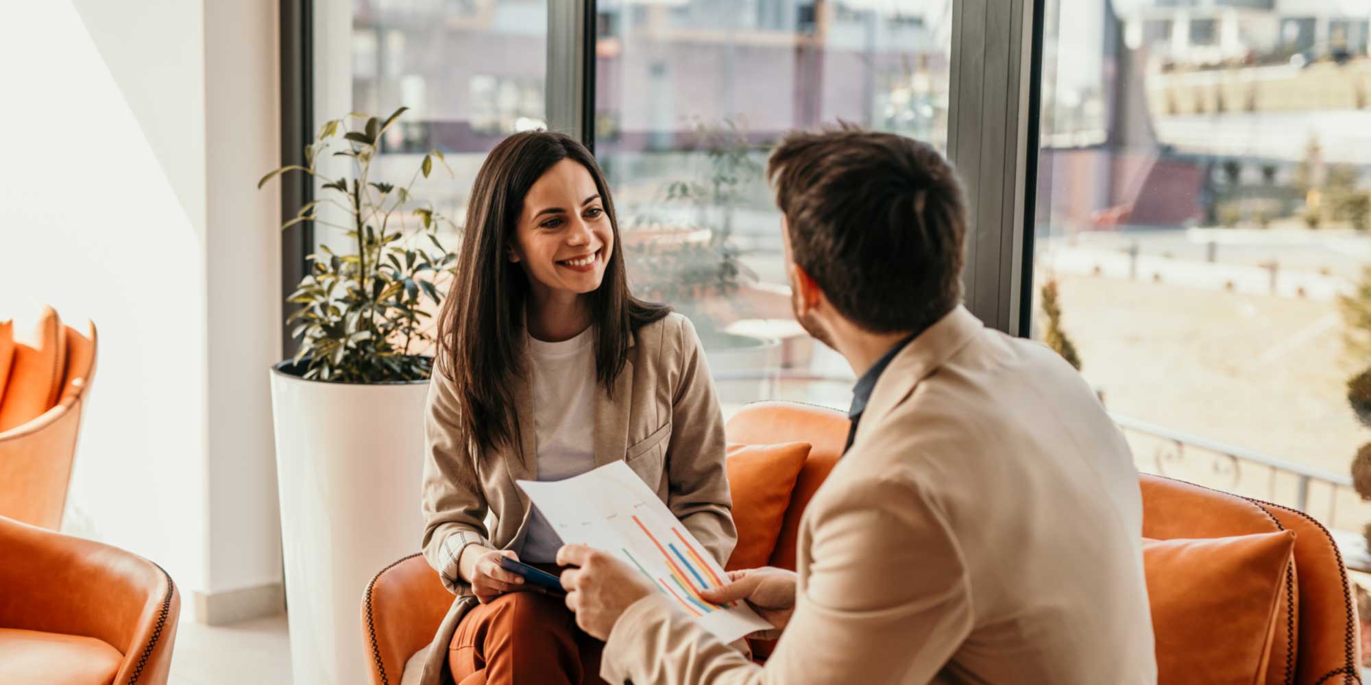 Two people seated in a modern office lounge, reviewing a document together during a discussion