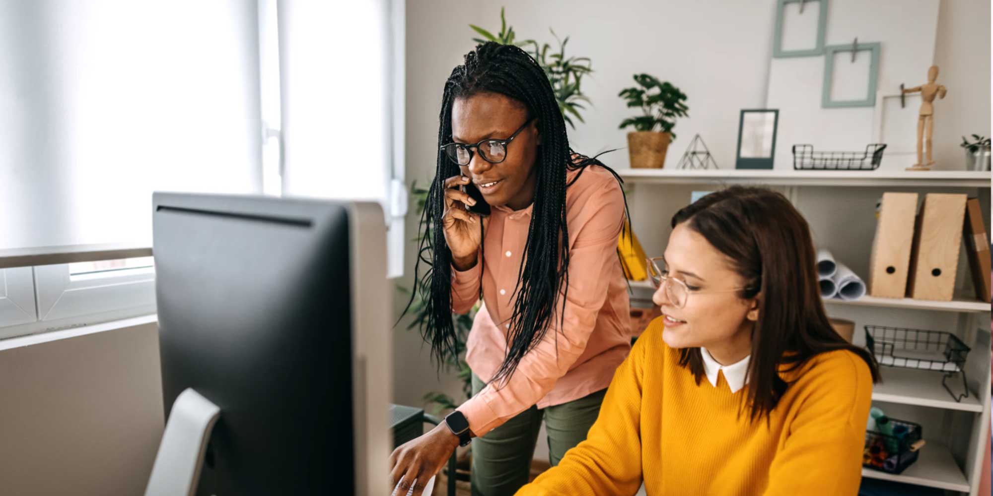 Female marketers discussing marketing plan at computer