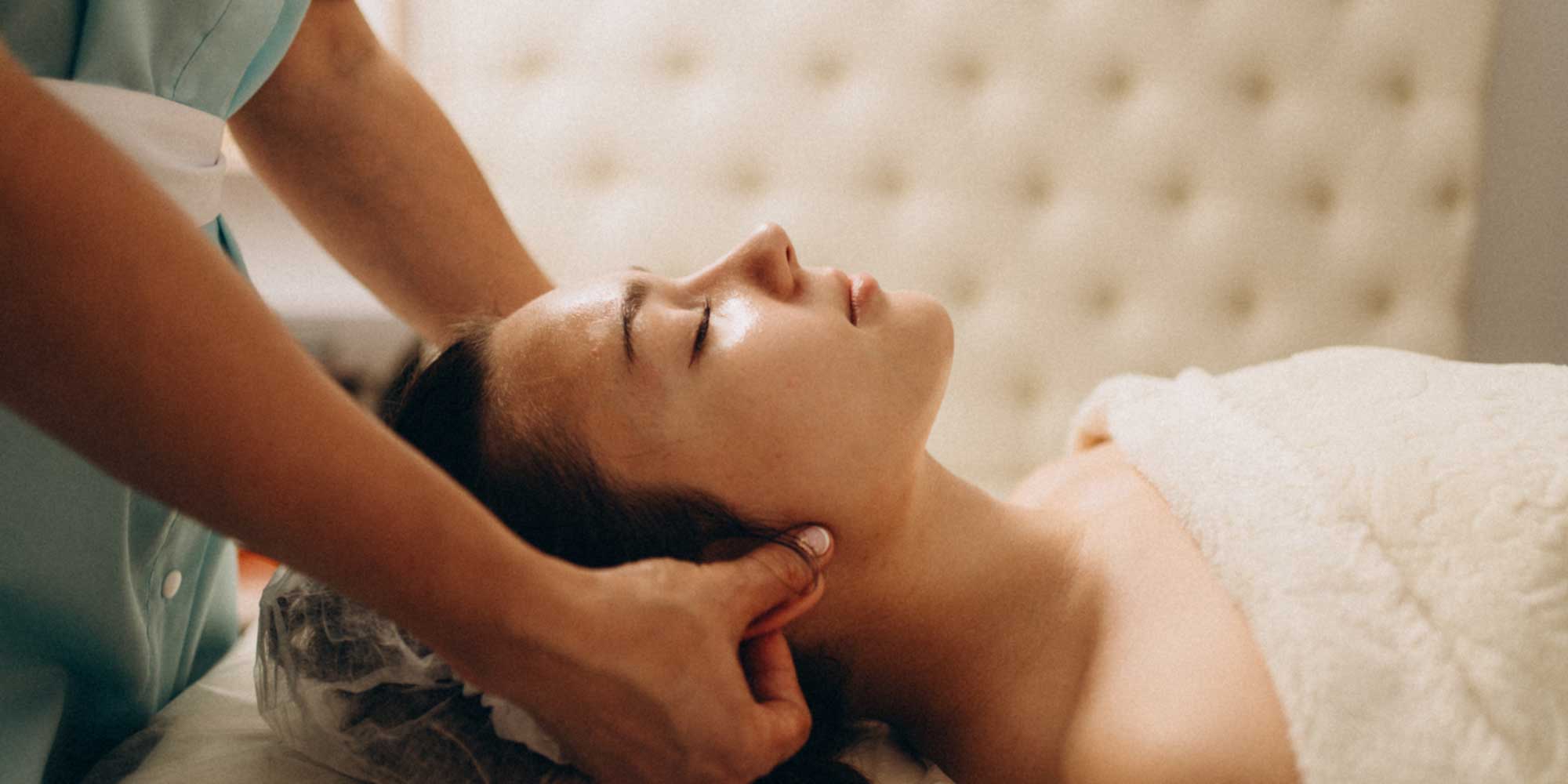 Massage therapist using both hands to massage a client’s neck