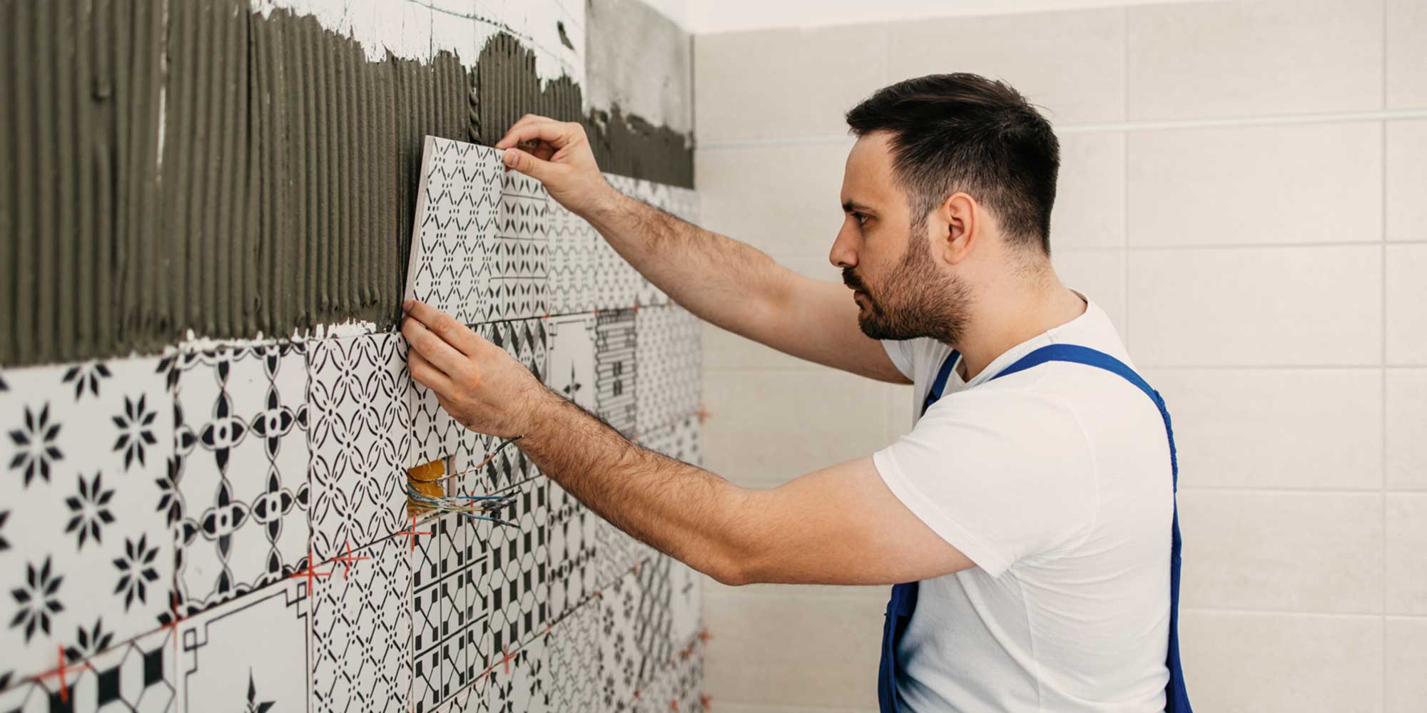 Man laying custom tile on a bathroom wall