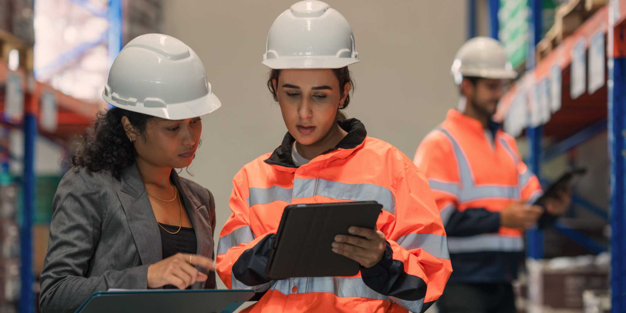 Logistics professionals reviewing operational data on a tablet inside a warehouse facility