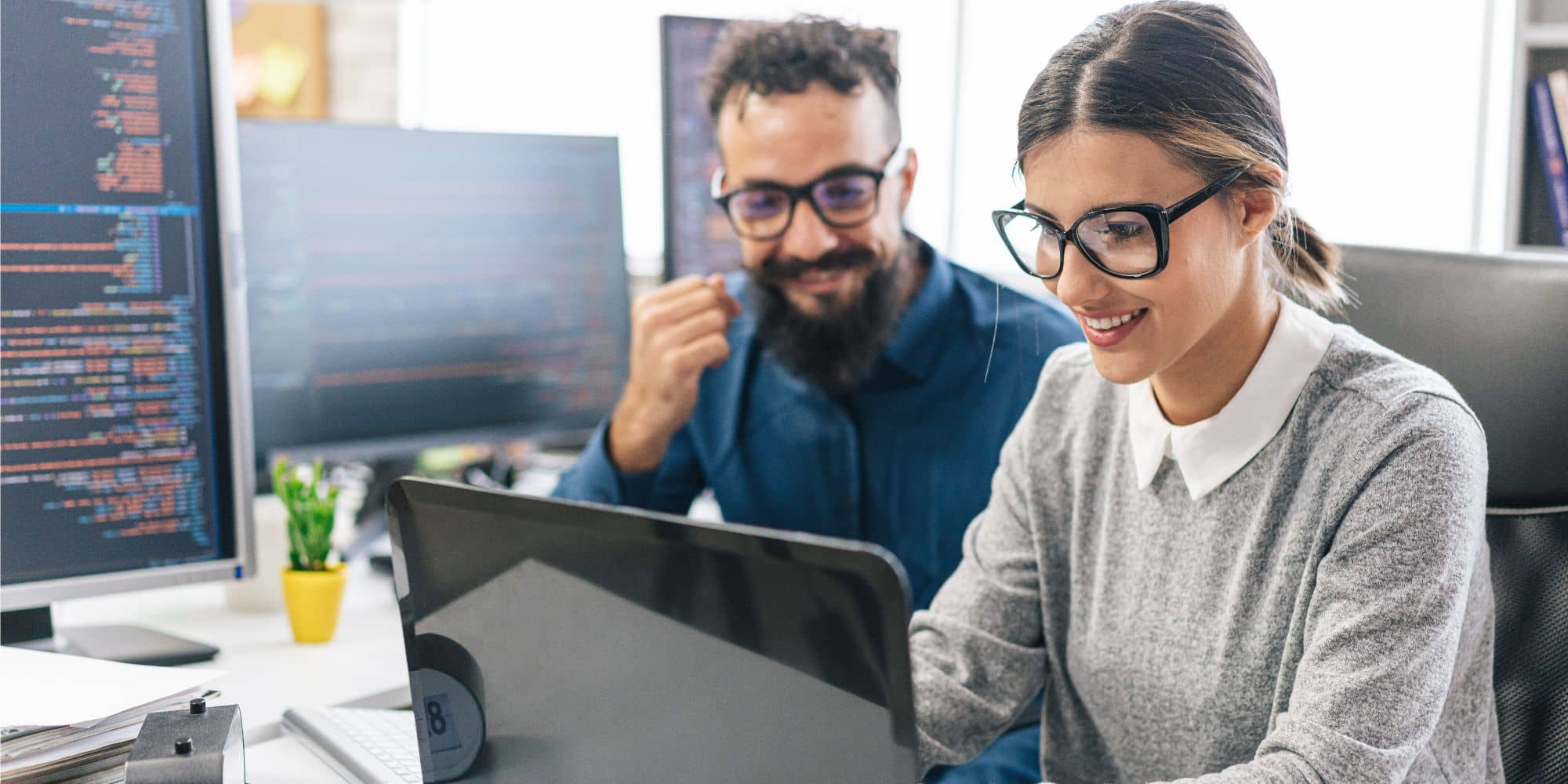 man and woman wearing glasses looking at a computer screen