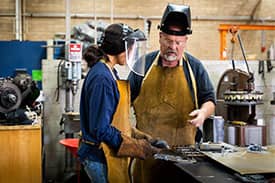 Workers operating machinery with protective gear in a manufacturing facility, illustrating workplace safety and risk management relevant to manufacturing insurance.