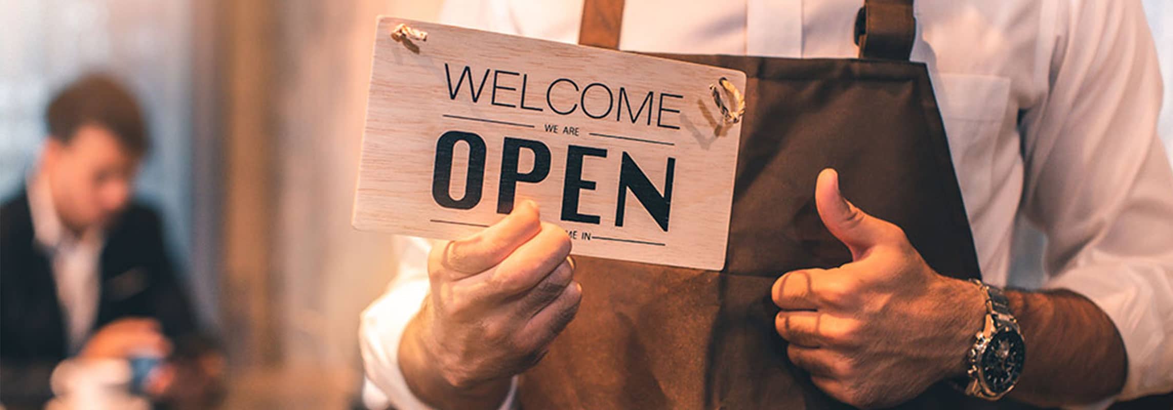 man holding welcome we are open sign