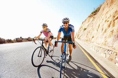 Man and woman cycyling by cliff