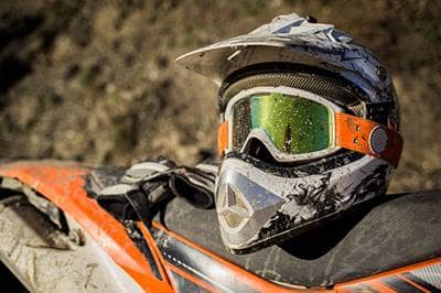 muddy helmet and goggles on ATV seat