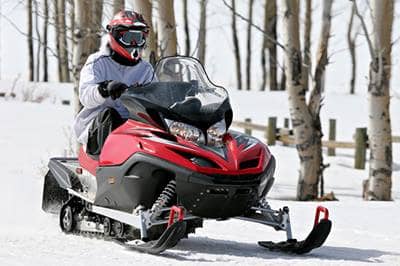 Person driving red and black snowmobile