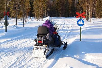 Driving snowmobile past snowmobile crossing sign