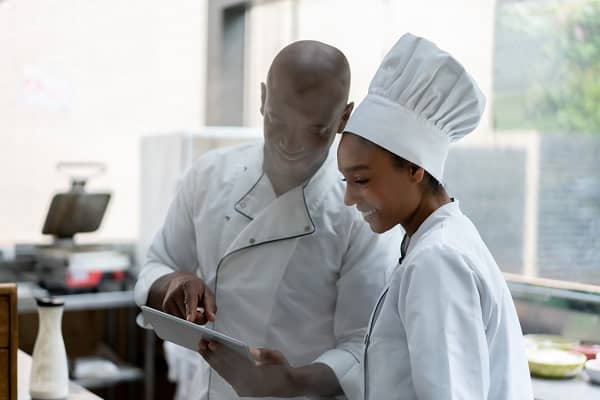 Cooks at a restaurant looking at the menu on a tablet computer 