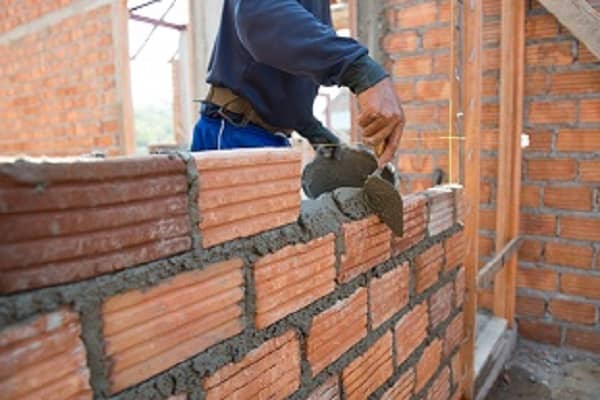 Worker building masonry house wall with bricks