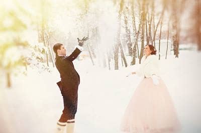 Newlyweds throwing snow during winter wedding